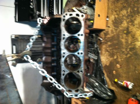 1996 Ford Bronco - Engine block with chain attached, showing cylinder bores.