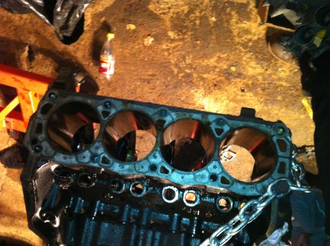 1996 Ford Bronco - Close-up of a disassembled engine block, showing the cylinder bores and surrounding metalwork.