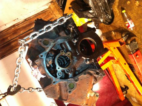 1996 Ford Bronco - Engine block with a chain attached, supported by an engine stand in a workshop environment.