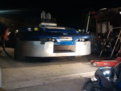 1995 Ford Probe - This modified blue car features a large custom front bumper and a hood scoop, seen in a garage setting.