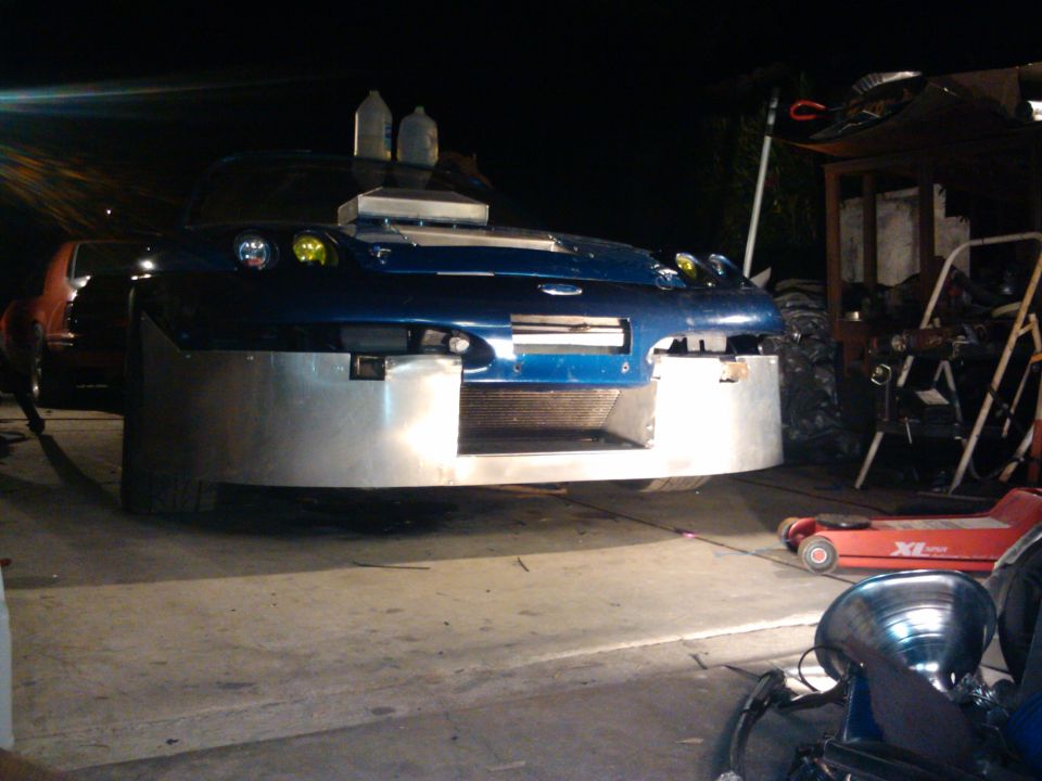 Blue car with custom front bumper and hood scoop, front view
