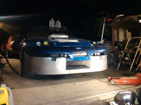 1995 Ford Probe - Customized blue car with a large front bumper and hood scoop, possibly undergoing modifications.