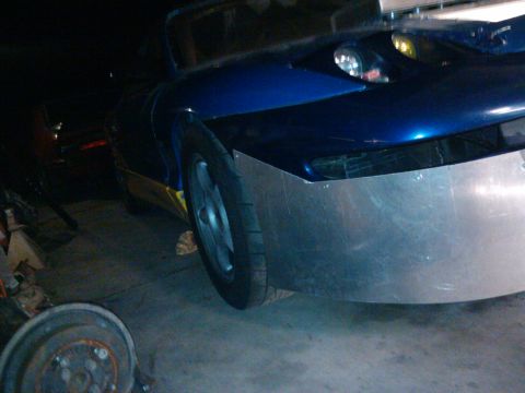 1995 Ford Probe - A blue car with a custom metal bumper and pop-up headlight is shown in a garage.