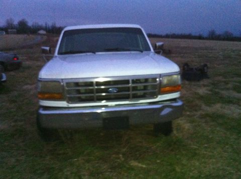 1992 Ford Bronco - Front view of a white 1992 Ford Bronco parked in a grassy field at dusk.