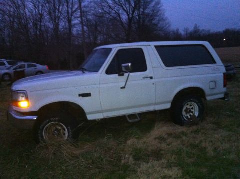 1992 Ford Bronco - A white 1992 Ford Bronco is parked in a field as dusk settles.