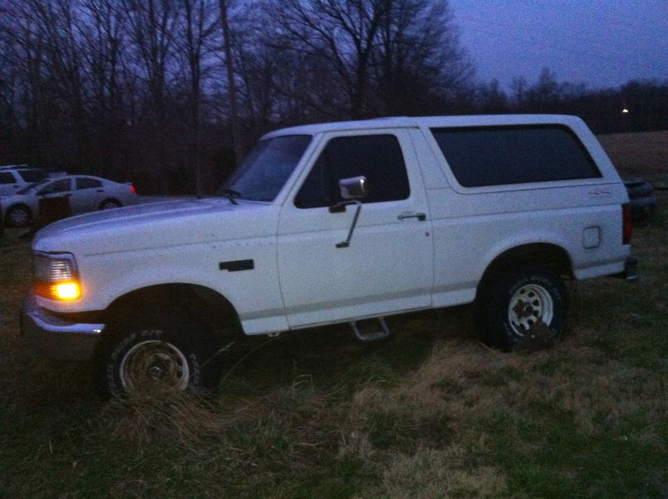 White 1992 Ford Bronco parked on grassy field at dusk