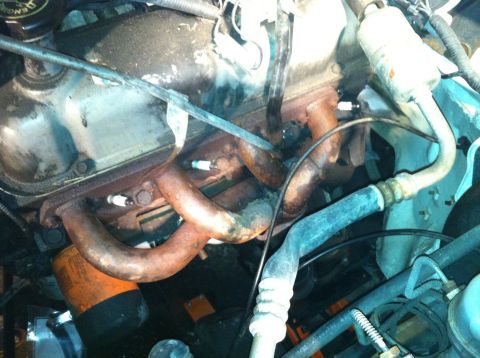 1992 Ford Bronco - The engine bay features an exhaust manifold with visible spark plugs and an oil filter. The hoses and wiring are also apparent.