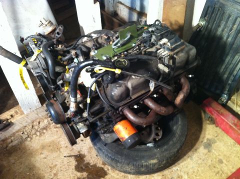 1992 Ford Bronco - Engine assembly with exhaust manifolds and oil filter visible, placed on a tire.