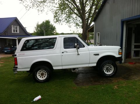 1992 Ford Bronco - A white 1992 Ford Bronco is parked on a grassy lawn next to a building.