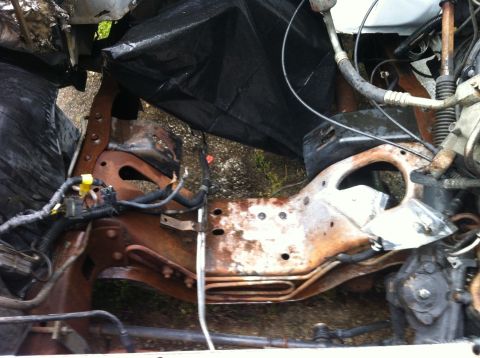 1992 Ford Bronco - Close-up view of a heavily rusted vehicle frame and engine parts, partially covered by black plastic.
