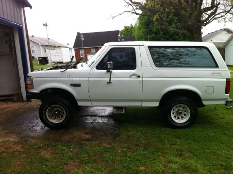 1992 Ford Bronco - Side view of a white 1992 Ford Bronco with its hood up, parked outdoors.