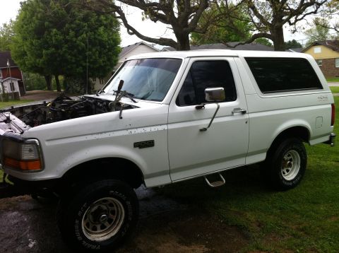 1992 Ford Bronco - This white Ford Bronco is parked outside with its hood open, revealing the engine compartment.