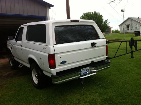 1992 Ford Bronco - A white 1992 Ford Bronco with a camper shell is parked on a grassy lawn next to a garage.