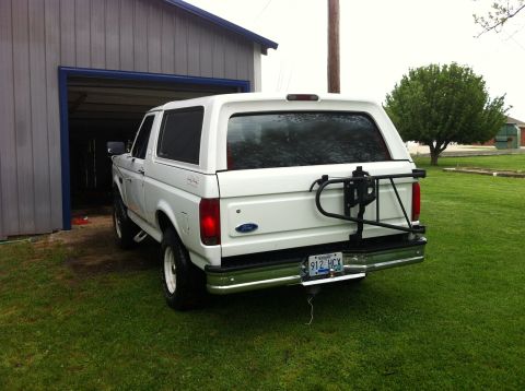 1992 Ford Bronco - This white 1992 Ford Bronco is parked in front of a garage, a rear-mounted spare tire carrier and a visible license plate.