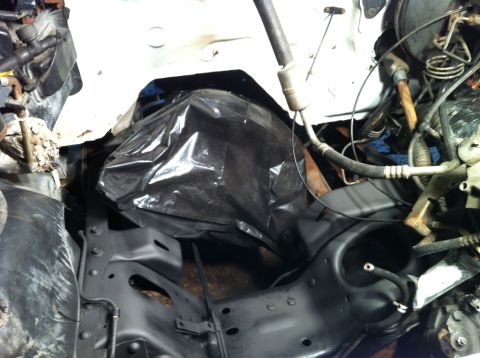 1992 Ford Bronco - A view into the engine bay, showing some components covered by black plastic sheeting.