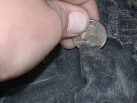 1994 Ford Bronco - Tire tread depth is being measured using a quarter coin to gauge wear.