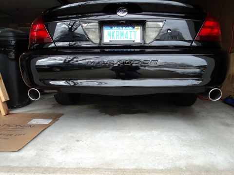 2004 Mercury Grand Marquis - The rear of a black sedan displays a 'Marauder' emblem and dual exhaust pipes.