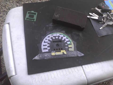 2003 Ford Crown Victoria - A car's dashboard gauge cluster is shown with keys and a sanding block nearby.