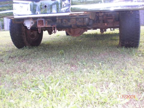 1993 Ford Bronco - The underside of a truck shows its rear axle, hitch, and tires on a grassy surface.