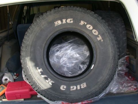 1994 Ford Bronco - Spare Bigfoot tire and a red toolbox are stored in the cargo area of a vehicle.