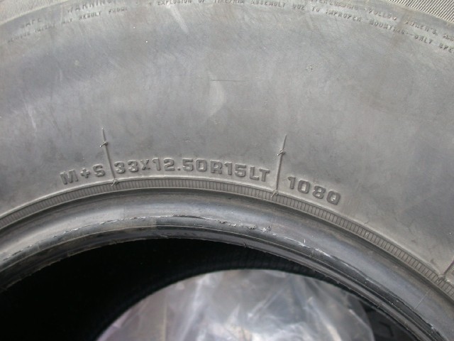 Close-up of tire sidewall showing size 33x12.50R15LT and DOT code 1080