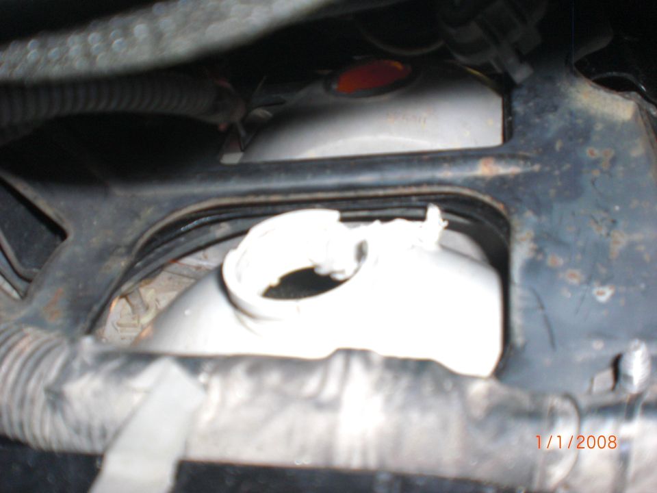 Close-up of a vehicle's coolant reservoir and surrounding metal bracketry