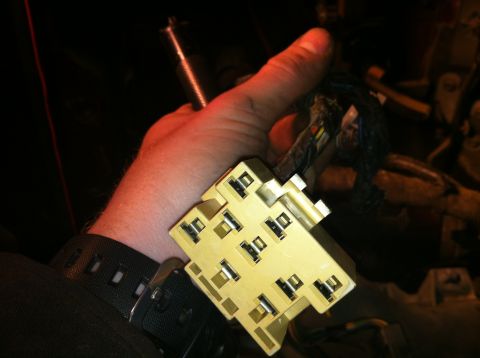 1996 Ford Bronco - A hand holds a yellow electrical connector with attached wires, likely part of a vehicle's wiring harness.