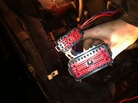 1996 Ford Bronco - Close-up of a hand connecting two red automotive wiring harness connectors.