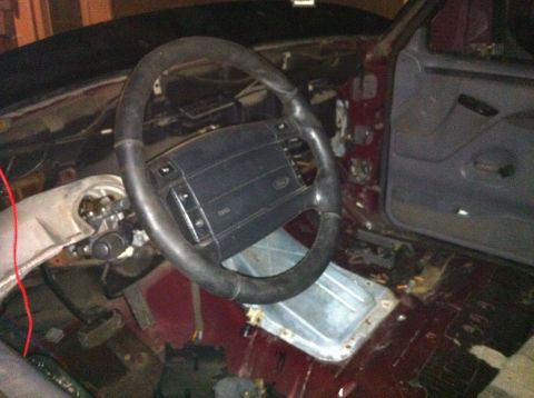 1996 Ford Bronco - The interior of a vehicle is shown with the dashboard and steering wheel disassembled, revealing internal components.