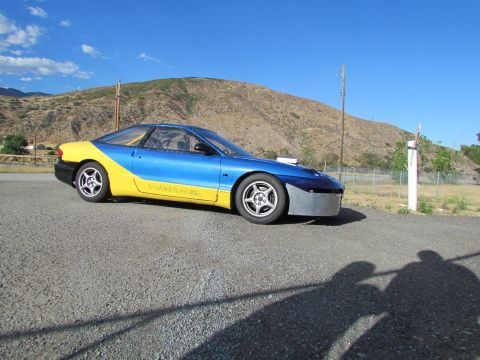 1995 Ford Probe - A modified Ford Probe with a two-tone paint job and racing modifications sits parked outdoors.