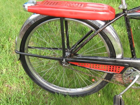 1994 Ford Bronco - Close-up of a vintage bicycle's rear wheel, fender, and red seat against a grassy background.