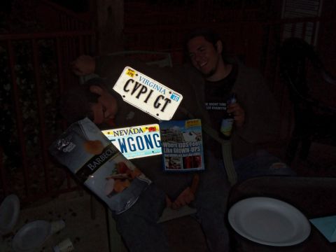 2000 Mercury Grand Marquis - License plates and snacks are scattered around a table with a person holding a beer.