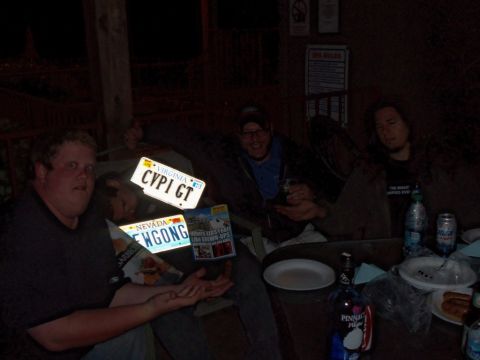 2000 Mercury Grand Marquis - A group of people are gathered around a table, holding up various license plates.