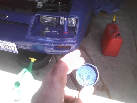 2003 Ford Crown Victoria - A blue car's front end is visible with an oil drain pan and a red gas can nearby.