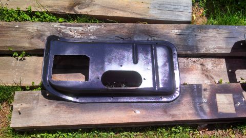 1979 Ford Bronco - Car door panel with cutouts for window crank and handle, laid out on wood planks.