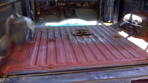 1979 Ford Bronco - The interior of a truck shows a red-primed bed and a disassembled cabin with visible wiring and controls.