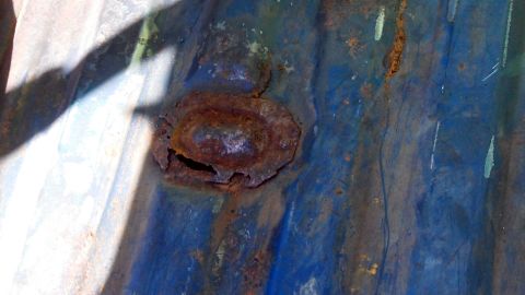 1979 Ford Bronco - Close-up of rusted metal with blue paint, likely a vehicle part.