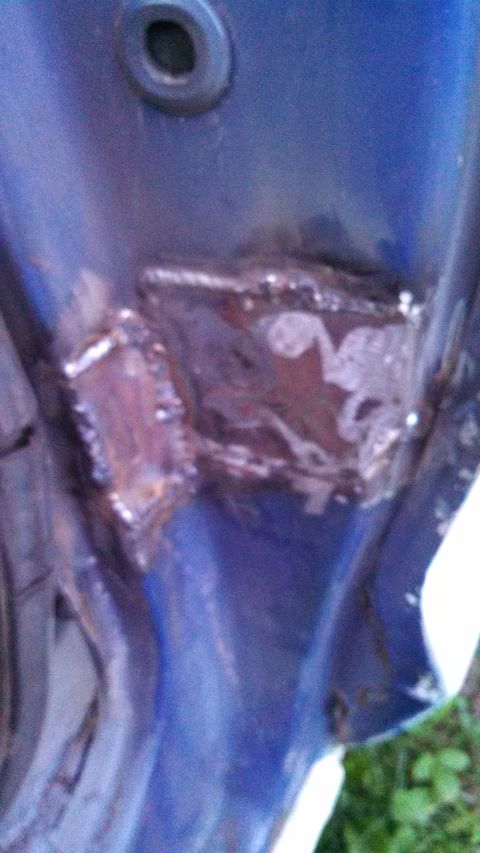 1979 Ford Bronco - Close-up of a blue car door showing areas of repair with visible welds.