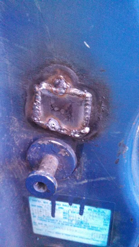 1979 Ford Bronco - Close-up of a welded metal part with a bolt and a sticker, set against a blue background.