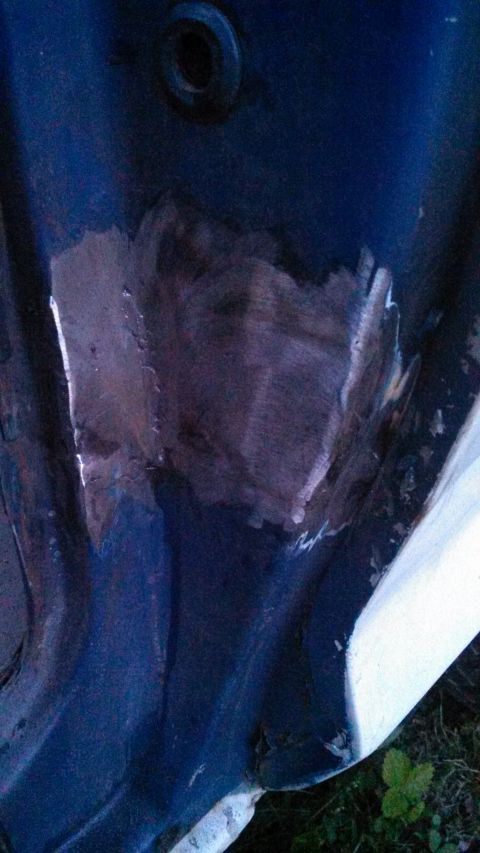 1979 Ford Bronco - A patch of metal has been welded onto a dark blue surface, which has a circular hole above it.