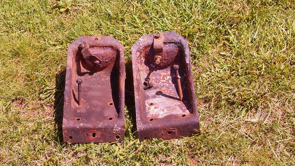Two rusty metal brackets on grass