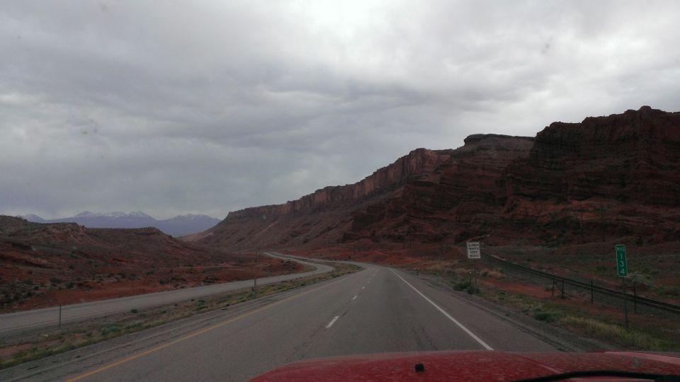 Red vehicle hood driving on highway through desert with red rock formations