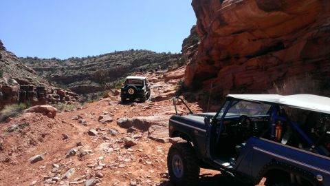 1994 Ford Bronco - Two Ford Broncos navigate a challenging rocky trail in a desert canyon.