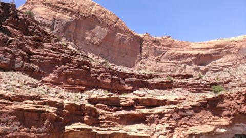 1994 Ford Bronco - Vast, layered sandstone cliffs dominate the landscape under a bright blue sky.