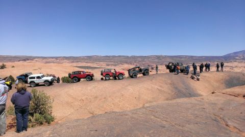 1994 Ford Bronco - Several off-road vehicles are parked on a desert ridge under a clear blue sky.