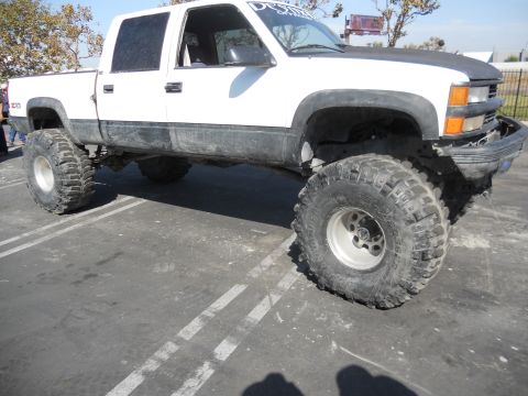 1986 Ford Bronco - This lifted Chevrolet C/K pickup truck features aggressive off-road tires and suspension modifications.