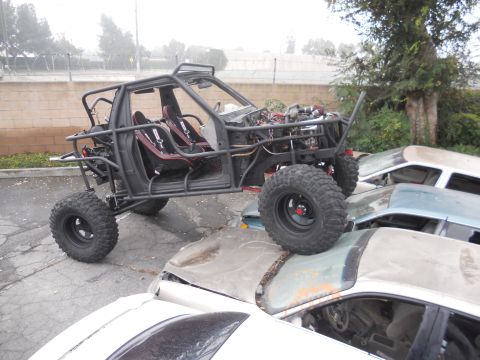 1986 Ford Bronco - A heavily modified off-road vehicle is perched atop a pile of abandoned cars.