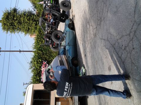 1986 Ford Bronco - A person photographs an off-road buggy perched atop a sedan.