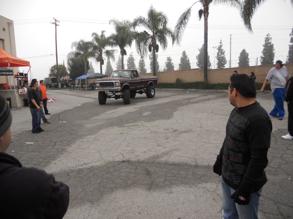 Brown lifted pickup truck with chrome grille, seen from a 3/4 front angle