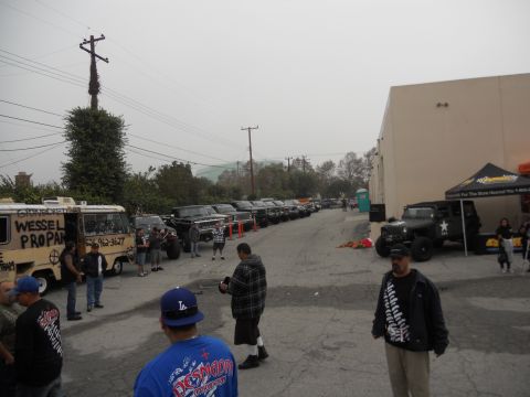 1986 Ford Bronco - A gathering of trucks and a van parked in an outdoor lot, with several people present.